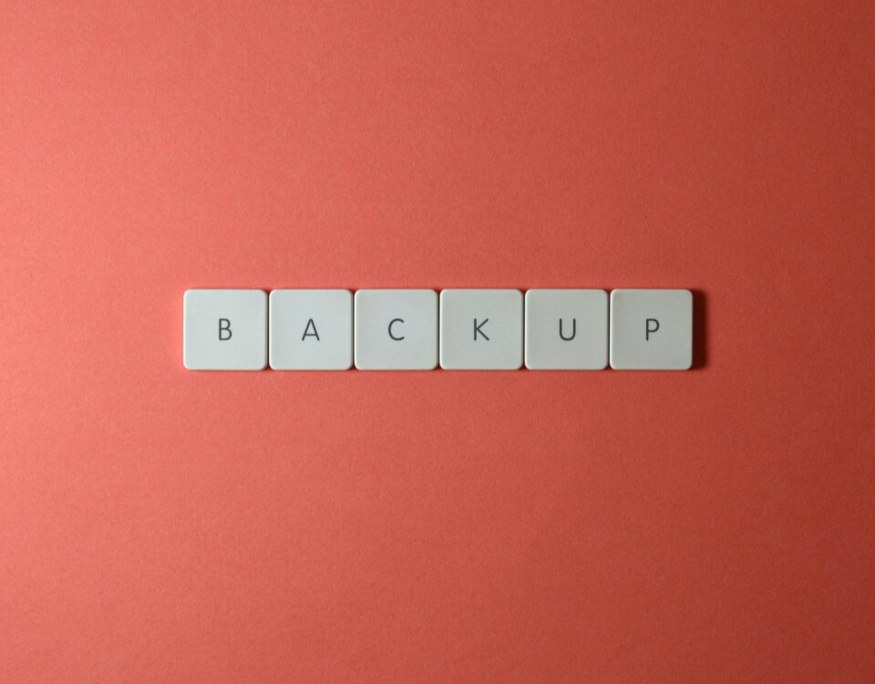 Free Close-up of keyboard keys spelling 'BACKUP' placed on a coral-colored surface. Stock Photo
