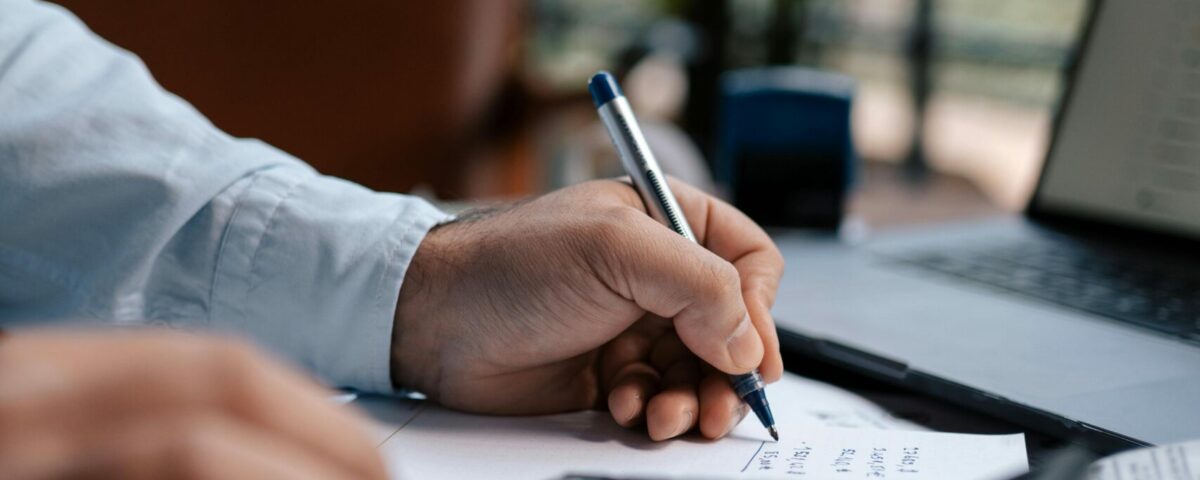 Free A person calculating finances with a calculator and pen on a desk indoors. Stock Photo