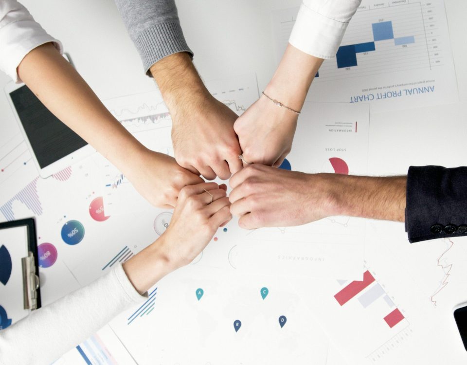 Free Colleagues celebrate success with a fist bump over financial charts depicting teamwork and unity. Stock Photo