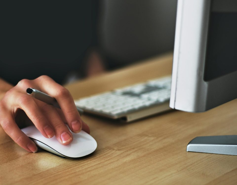 Free A hand using a wireless mouse at a modern desk setup with a computer and keyboard. Stock Photo