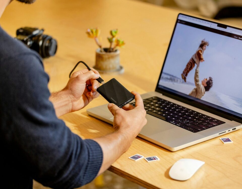 A man sitting at a table with a laptop and cell phone