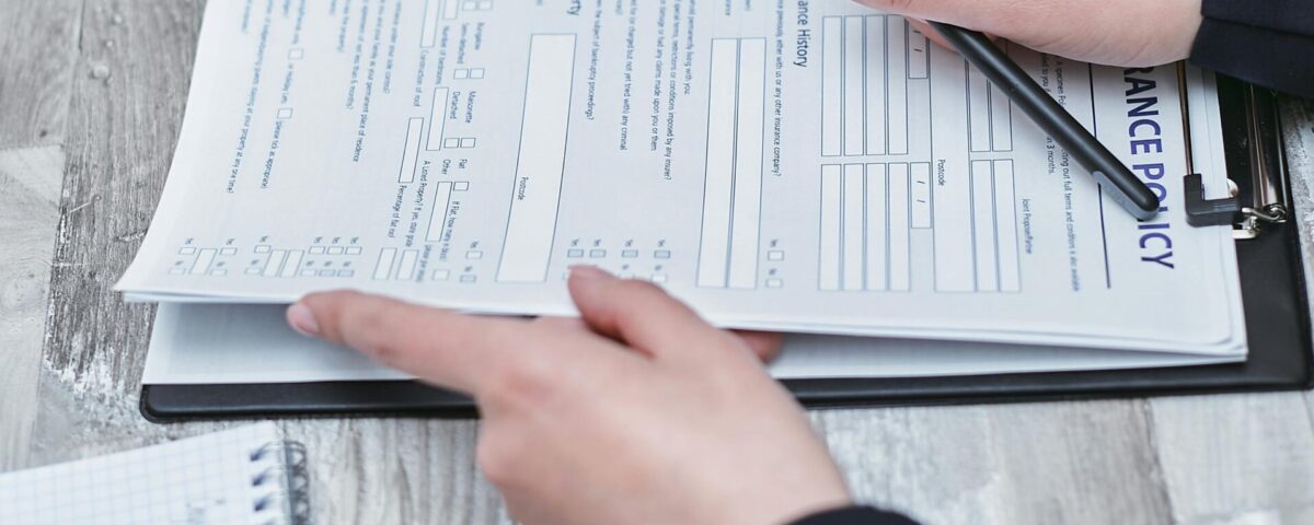 Free Close-up of hands analyzing insurance policy paperwork with pen on table. Stock Photo
