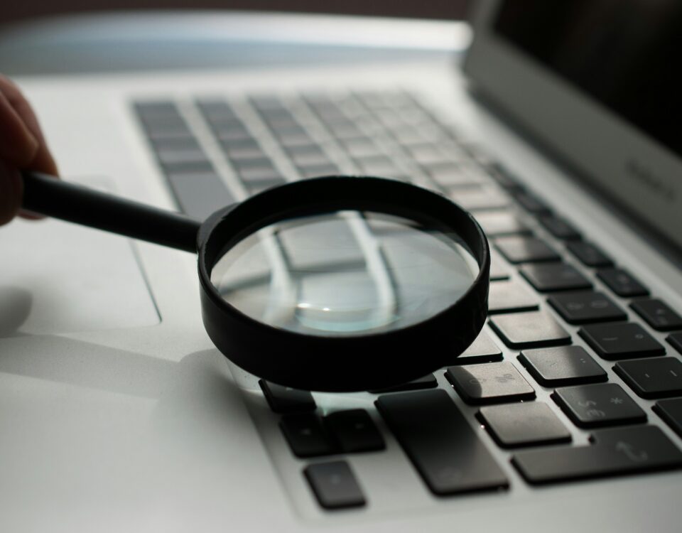 magnifying glass near gray laptop computer